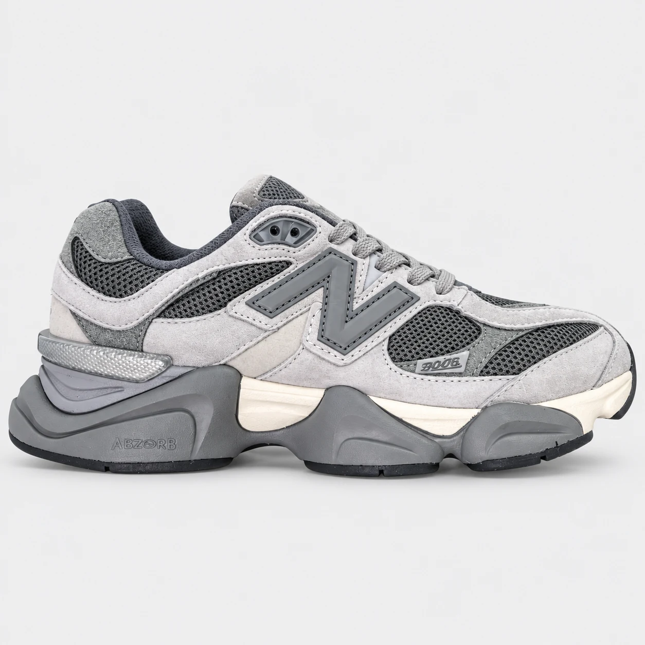 New Balance 9060 — Grey / Charcoal / Cream Grey / Charcoal / Cream low-top sneaker with lace-up fastening, layered panels and visible N branding. Browse both the cleaned catalogue image and original supplier photo, and select your UK size from 3 to 9.