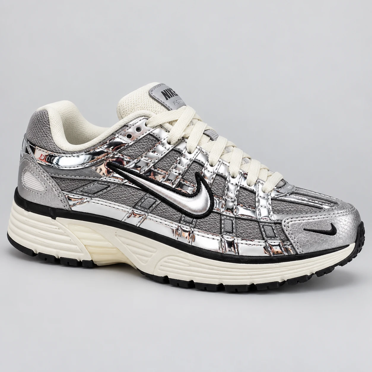 Nike P-6000 — Silver / Grey / Cream A silver and grey low-top sneaker with glossy layered overlays, cream laces and a cream sole edged in black. Choose a UK size from 3 to 9 and view the product photos at The Drip Society.