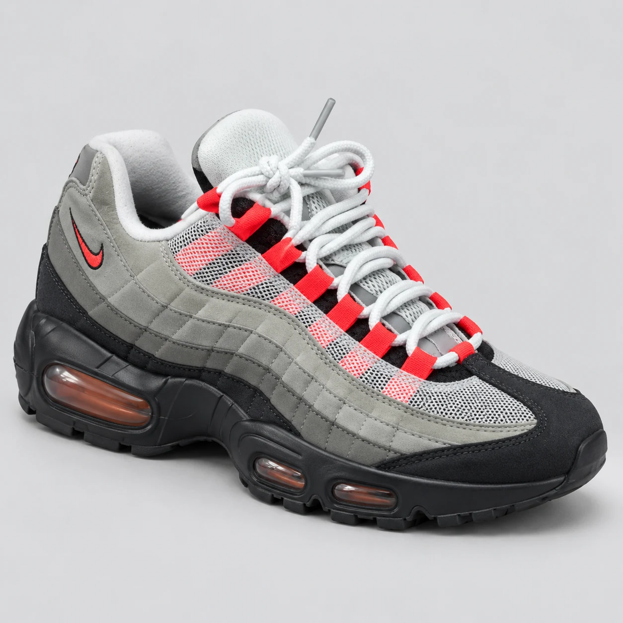 Nike Air Max 95 — Grey / Black / Red A grey low-top sneaker with layered side panels, red lace loops, a small red Swoosh and visible windows in the black sole. Choose a UK size from 3 to 9 and view the product photos at The Drip Society.
