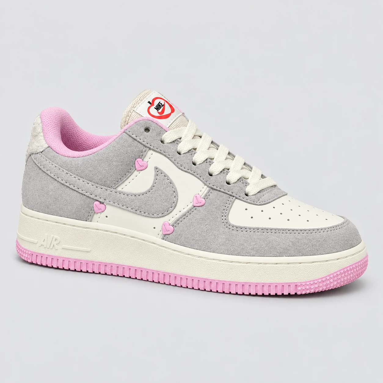 Nike Air Force 1 — Grey / Cream / Pink Hearts A grey and cream low-top sneaker with pink heart accents, cream laces, a perforated toe and pink outsole edging. Choose a UK size from 3 to 9 and view the product photos at The Drip Society.